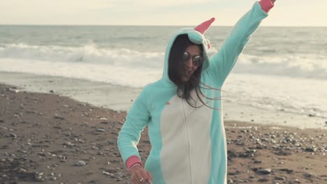 mujer con disfraz de unicornio bailando en la playa