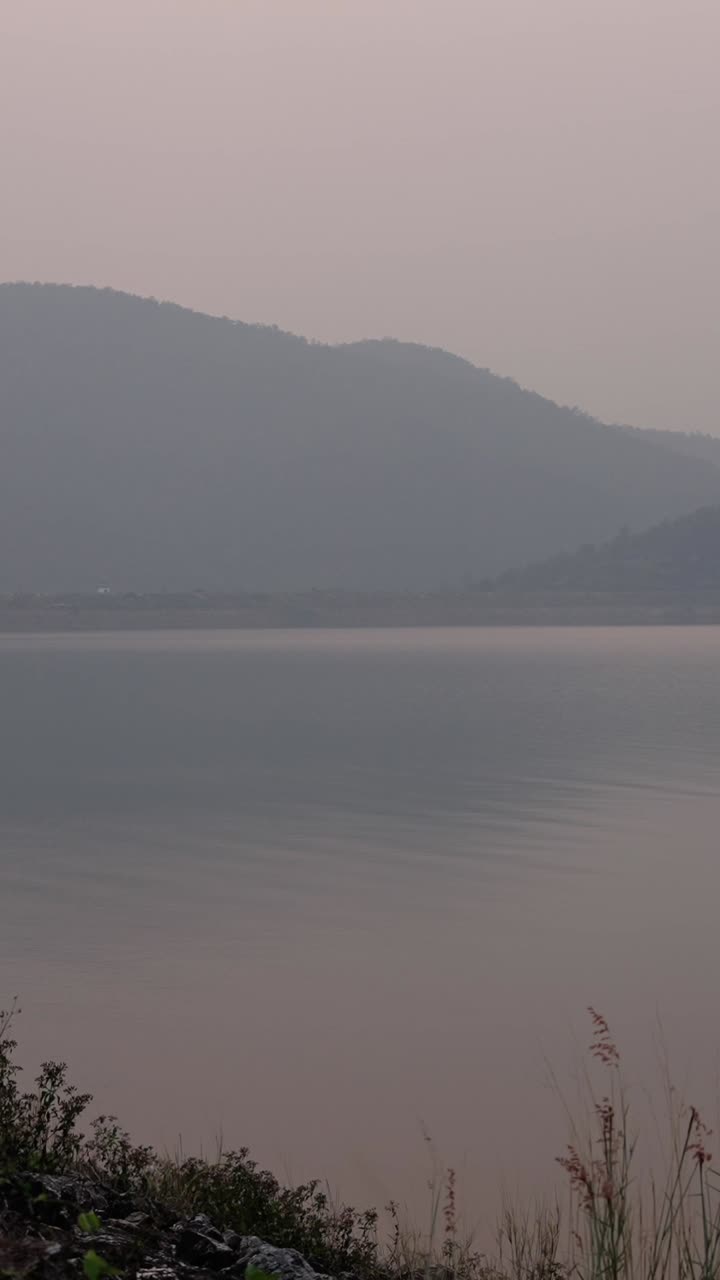 A tranquil lake surrounded by mountains at sunrise
