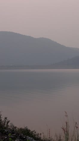 A tranquil lake surrounded by mountains at sunrise