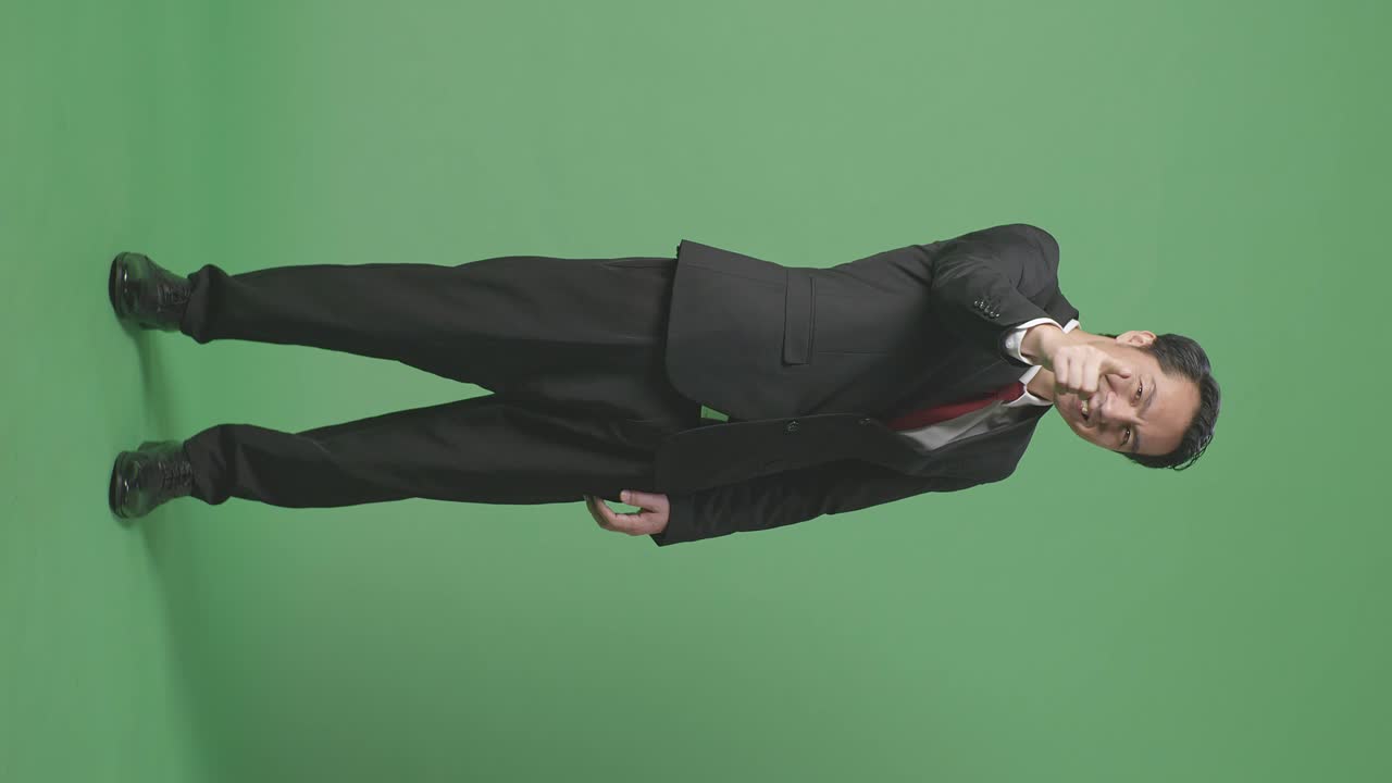 아시안 사업가의 몸이 가득 차 있습니다. 미소 짓고 스튜디오의 녹색 스크린 배경에서 정직한 몸짓을 합니다.