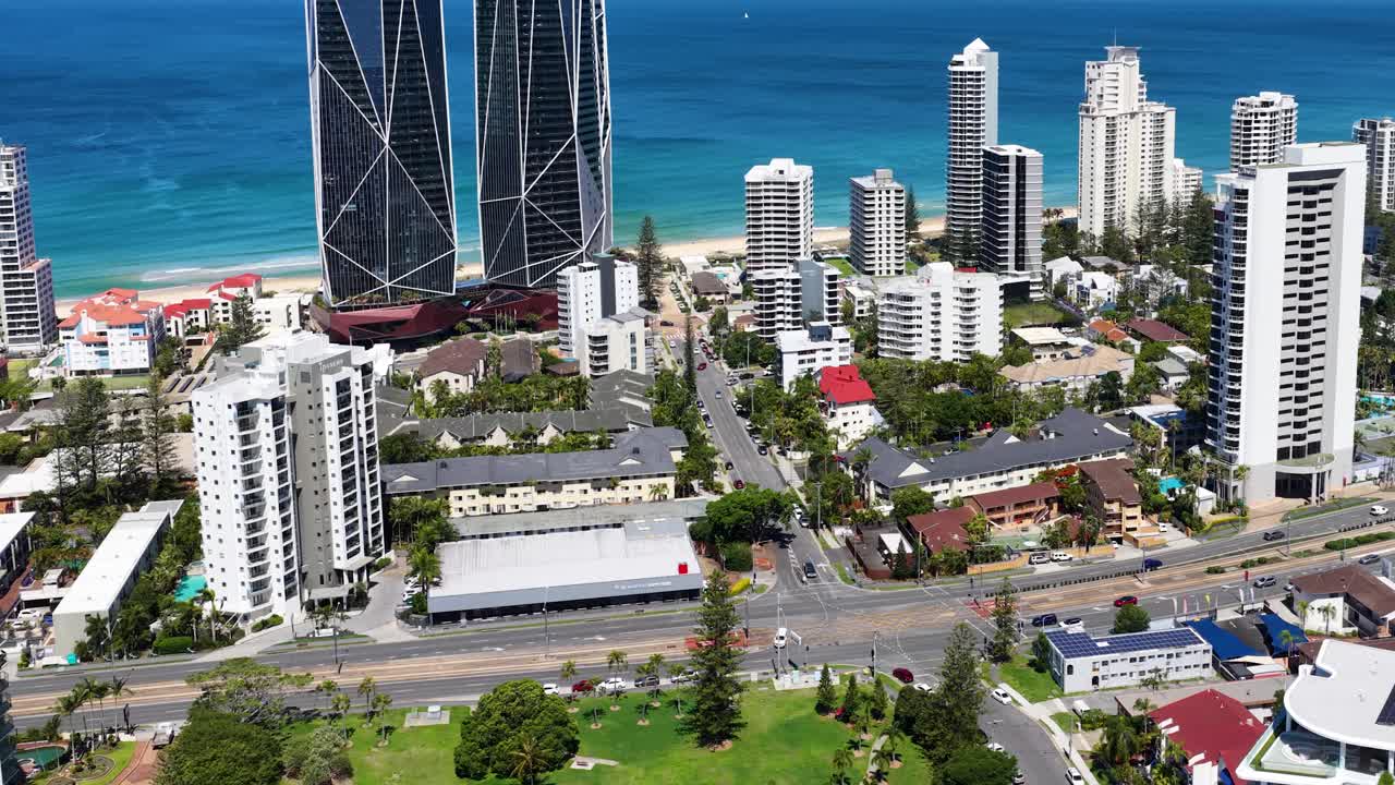 Drone ascends above Broadbeach Waters, revealing modern skyscrapers, coastline, and bright daylight scenery