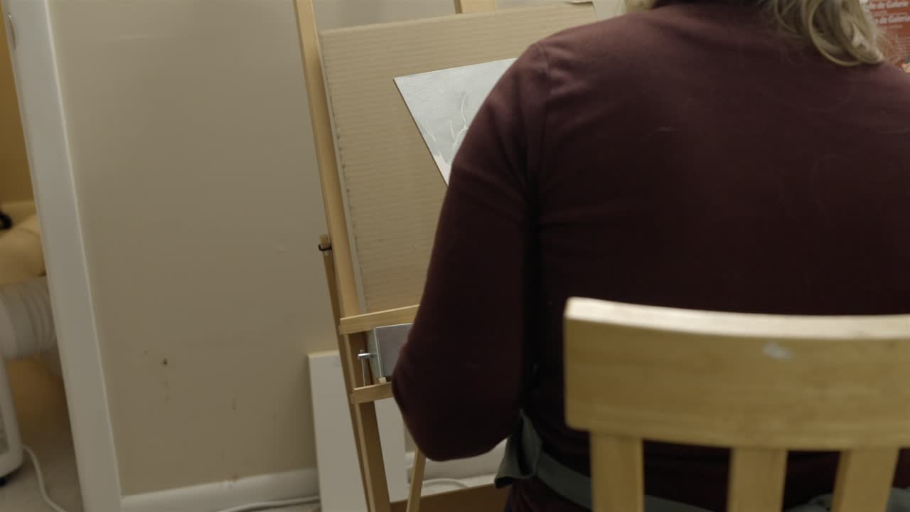 Artista pintando en su escritorio en un auténtico estudio de arte, vista trasera.