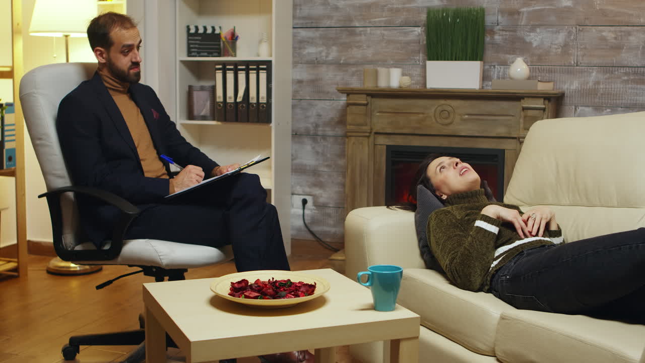 심리치료사는 불행한 여성이 있는 동안 메모를 취합니다.