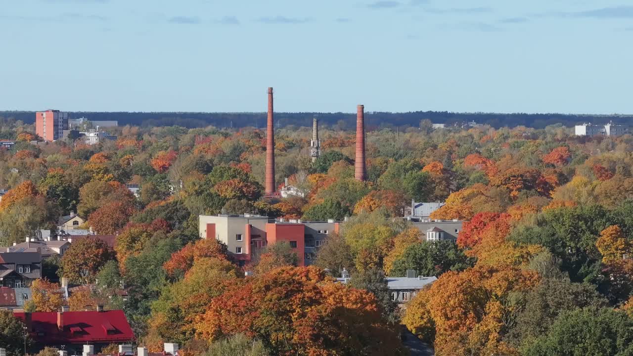Drone glides above colorful Pārdaugava with fall trees, chimneys in Riga, Latvia