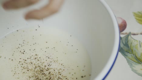 agregar especias a la leche de mantequilla dentro de un plato hondo blanco
