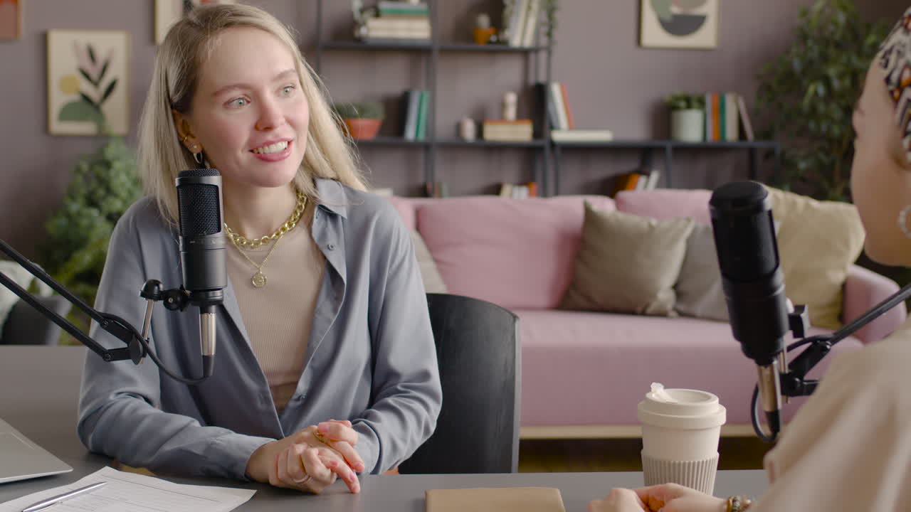 Rear View Of A Woman Recording A Podcast Talking Into A Microphone With Another Woman Sitting At Desk