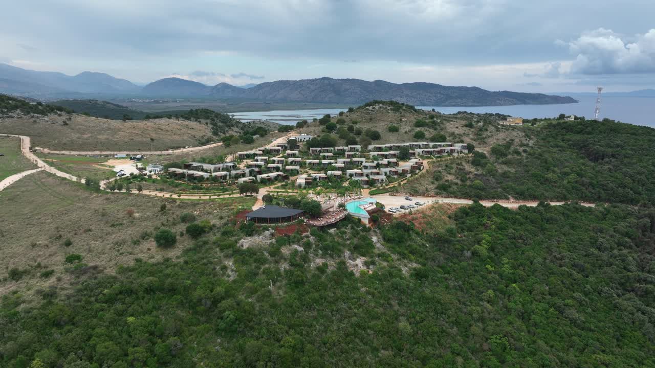 Wide aerial parallax of seaside village on green hill in rural Albania