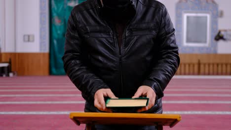 old maksed man reads the quran in mosque