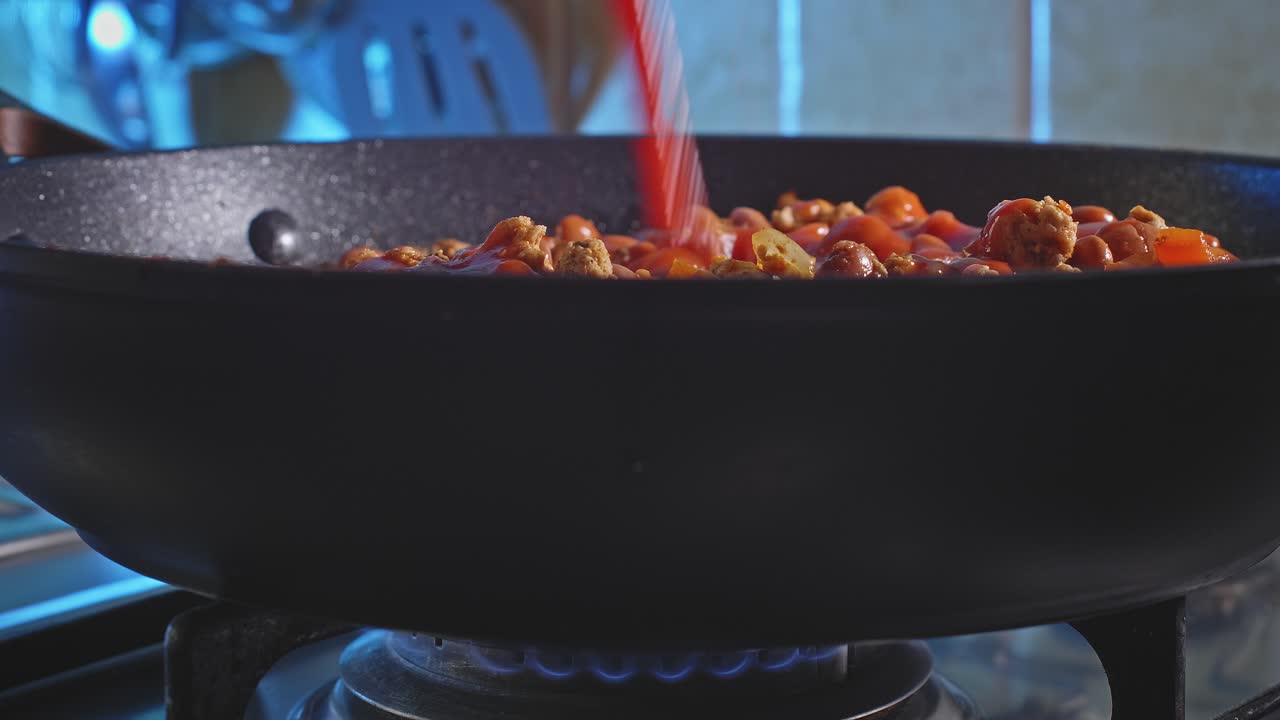 Vista laterale di succo di pomodoro versato nel tacchino piccante con fagioli che cuoce in padella a fuoco basso.