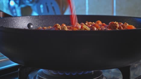 Vista-Lateral-Del-Jugo-De-Tomate-Que-Se-Vierte-En-Pavo-Picante-Con-Frijoles-Cocinados-En-Una-Sartén-A-Fuego-Lento