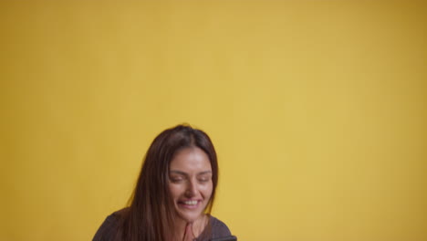 studio shot of excited couple with mobile phone celebrating winning money against yellow background 2