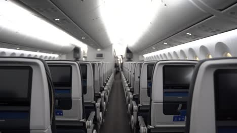 aisle of a widebody commercial airplane showing inflight entertainment displays.