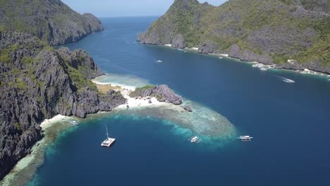 4k aerial drone view of private island star beach in palawan philippines with yacht in bay and local tour boats of philippines