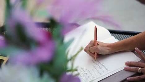 Toma-En-Cámara-Lenta-De-Una-Persona-Firmando-Un-Libro-De-Invitados-En-Una-Recepción-De-Bodas