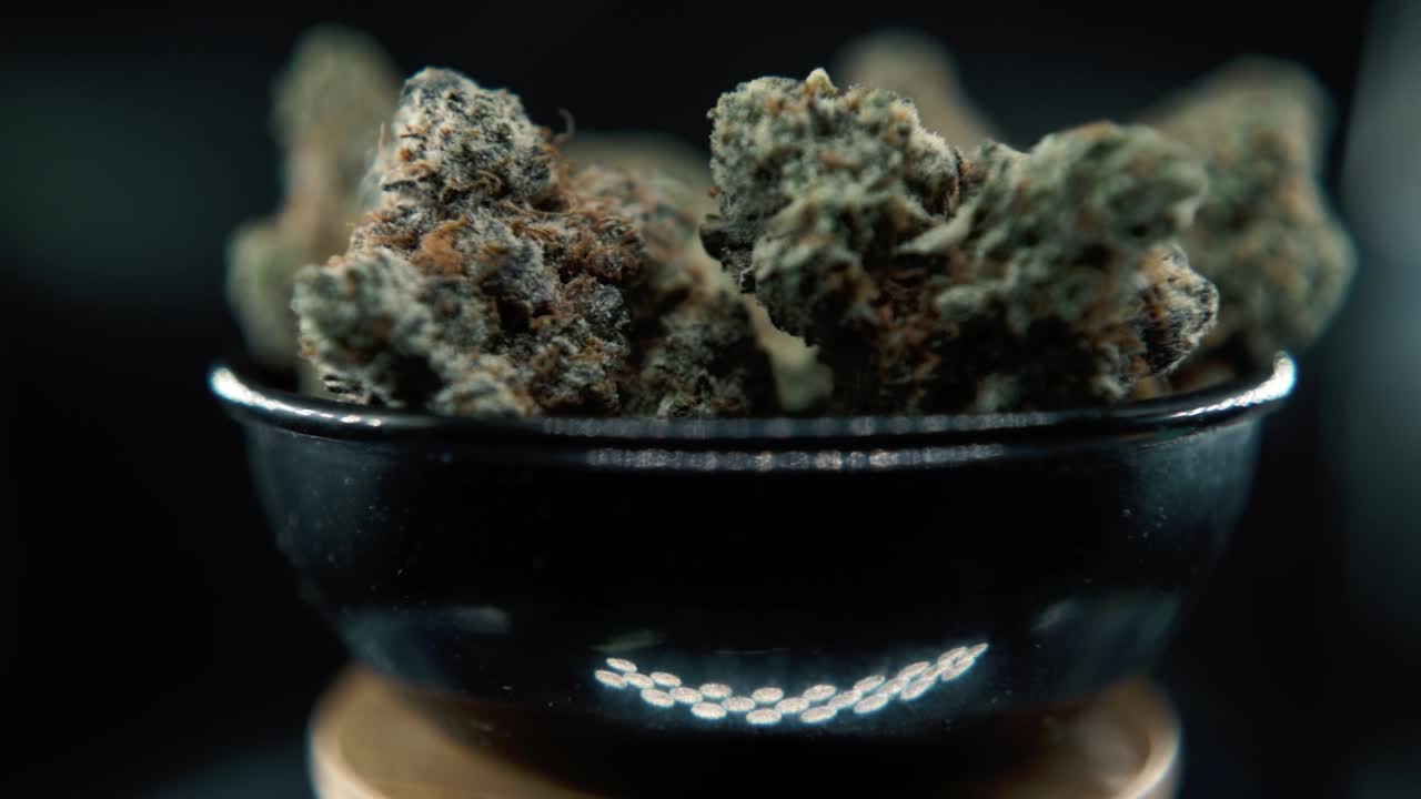 A macro detailed STEADY shot of a cannabis plant, hybrid orange strains, sativa ,marijuana flower, on a rotating stand, Full HD, super slow motion, 120 fps, studio lighting