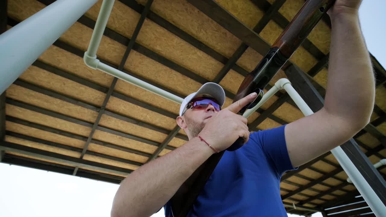 스포츠맨이 이중 배럴 건으로 총을 고, 슈팅 테스트를 위한 스포츠 경기장은 날아다니는 스케이트를 고 있습니다.