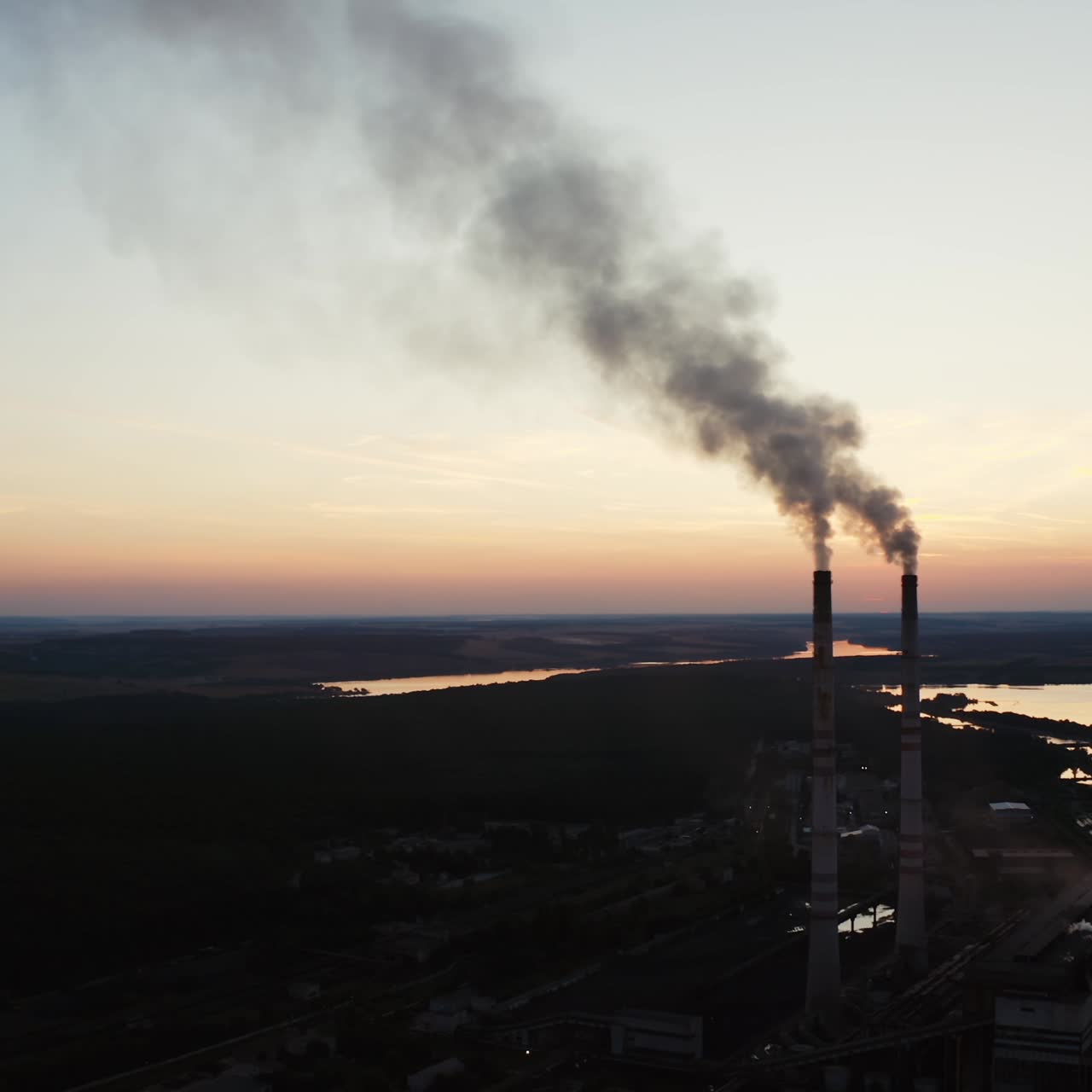 Factory tubes on the sunset background. Smoke from the pipes. Pollution concept. Video from the air.