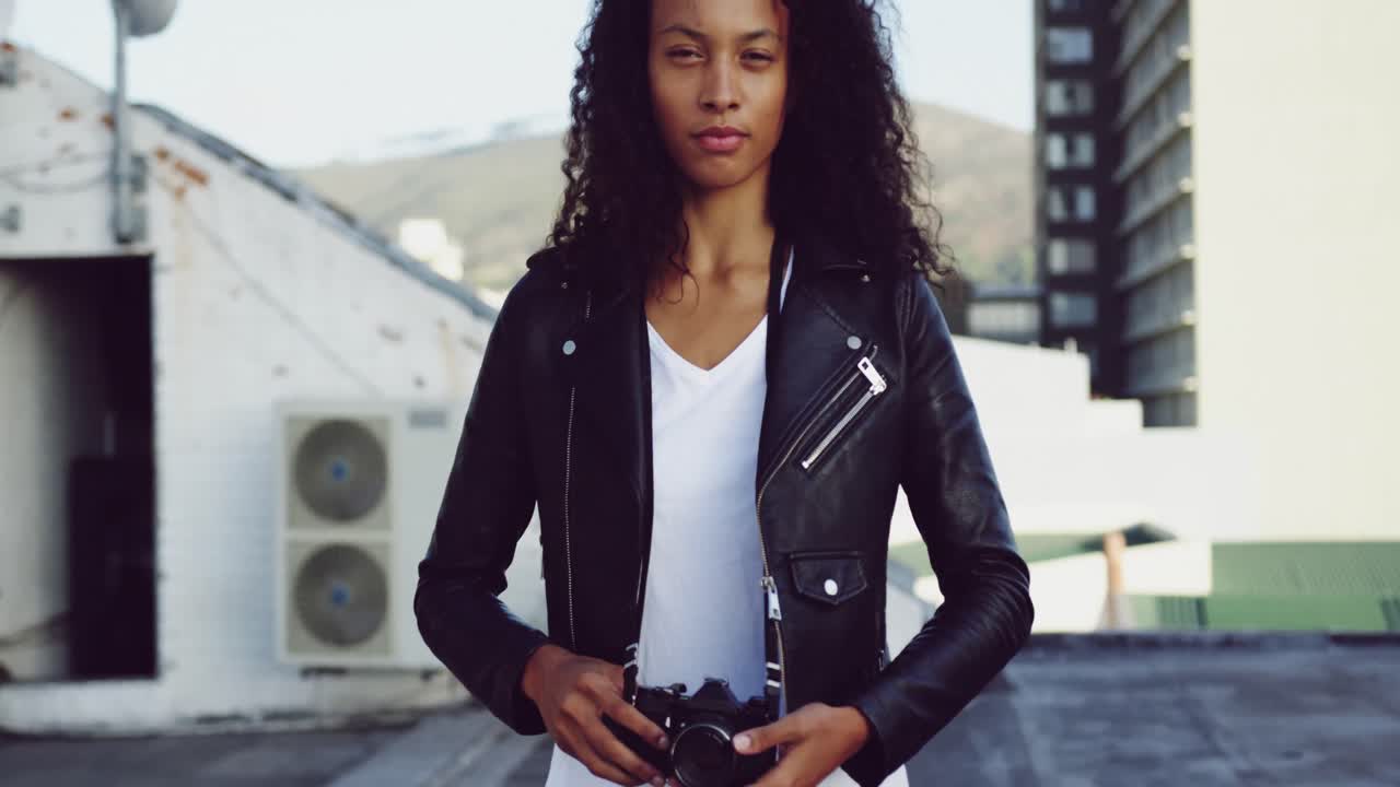 Fashionable young woman on urban rooftop holding a camera