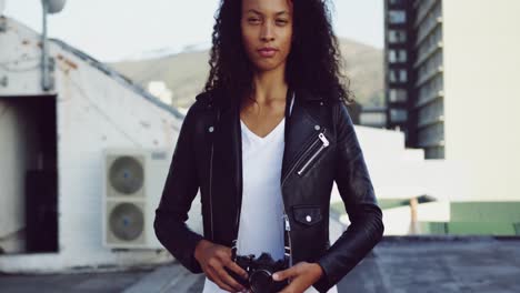 Fashionable-young-woman-on-urban-rooftop-holding-a-camera