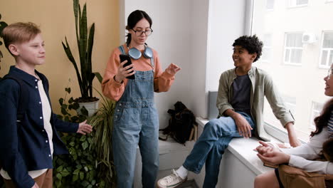 diverse group of teenagers socializing and interacting with a smartphone indoors