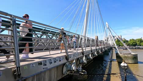 people walking on hungerford bridge in london