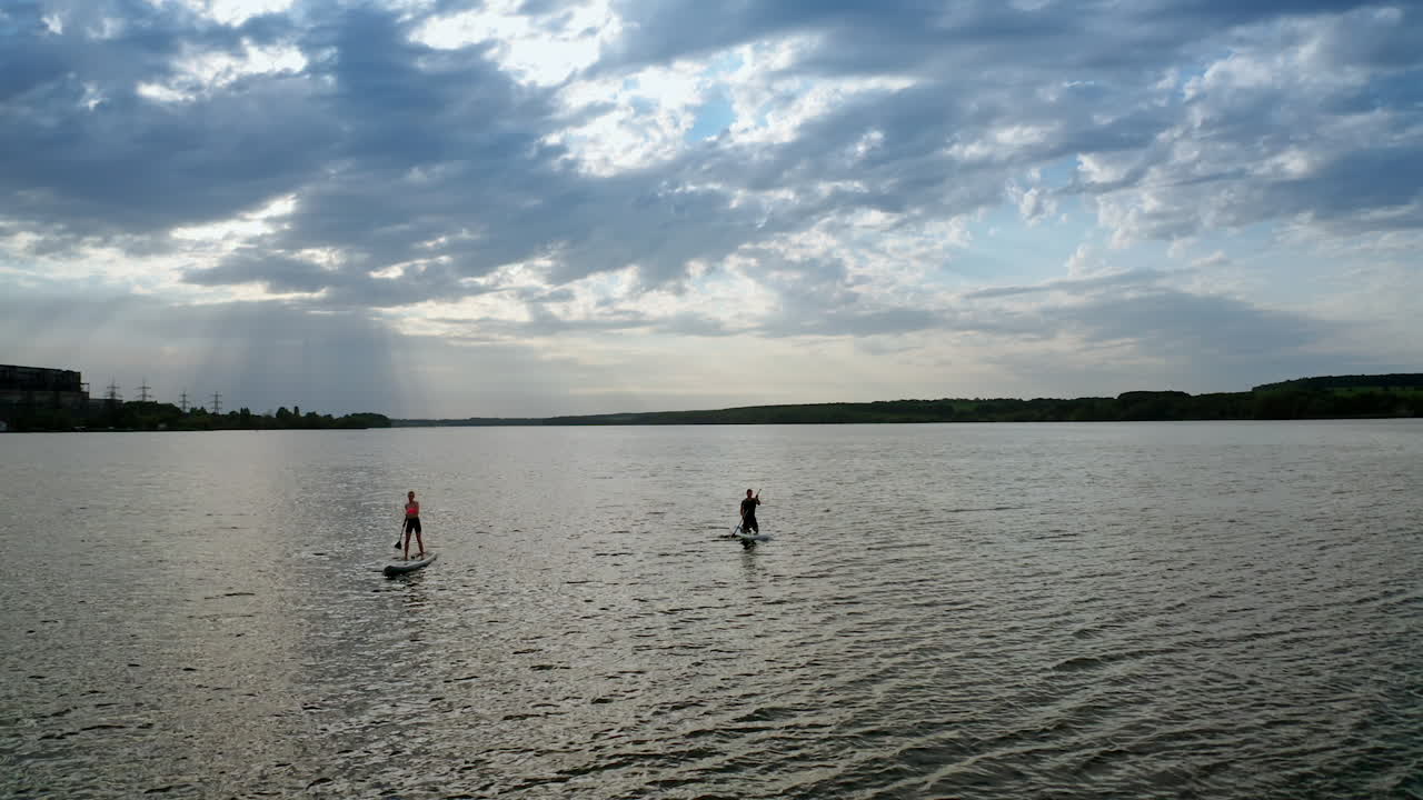 Couple relaxing on paddle sup board. Drone view of couple relaxing on stand up paddle board