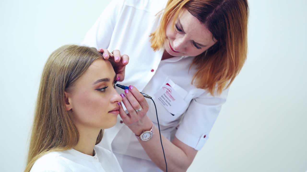 Optometrist treating woman's eyes in clinic. Specialist works with medical instrument for eye care in clinic. Eye diagnostic.