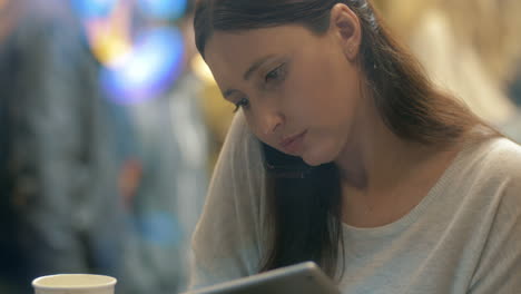 woman busy with phone talk and using pad in cafe