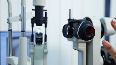 panning shot of female ophthalmologist`s hand doing eye exam with slit lamp. preparing special technic for checking eyesight. selective focus.