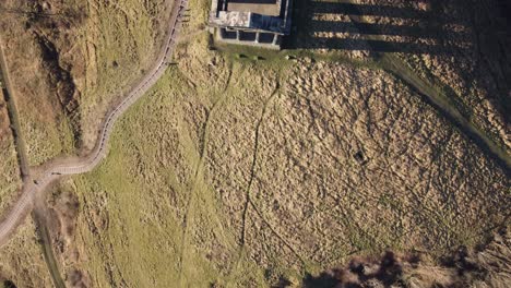 aerial bird's eye view over an ancient historical pillar structure with tourists wallking upto the hill top at sunset