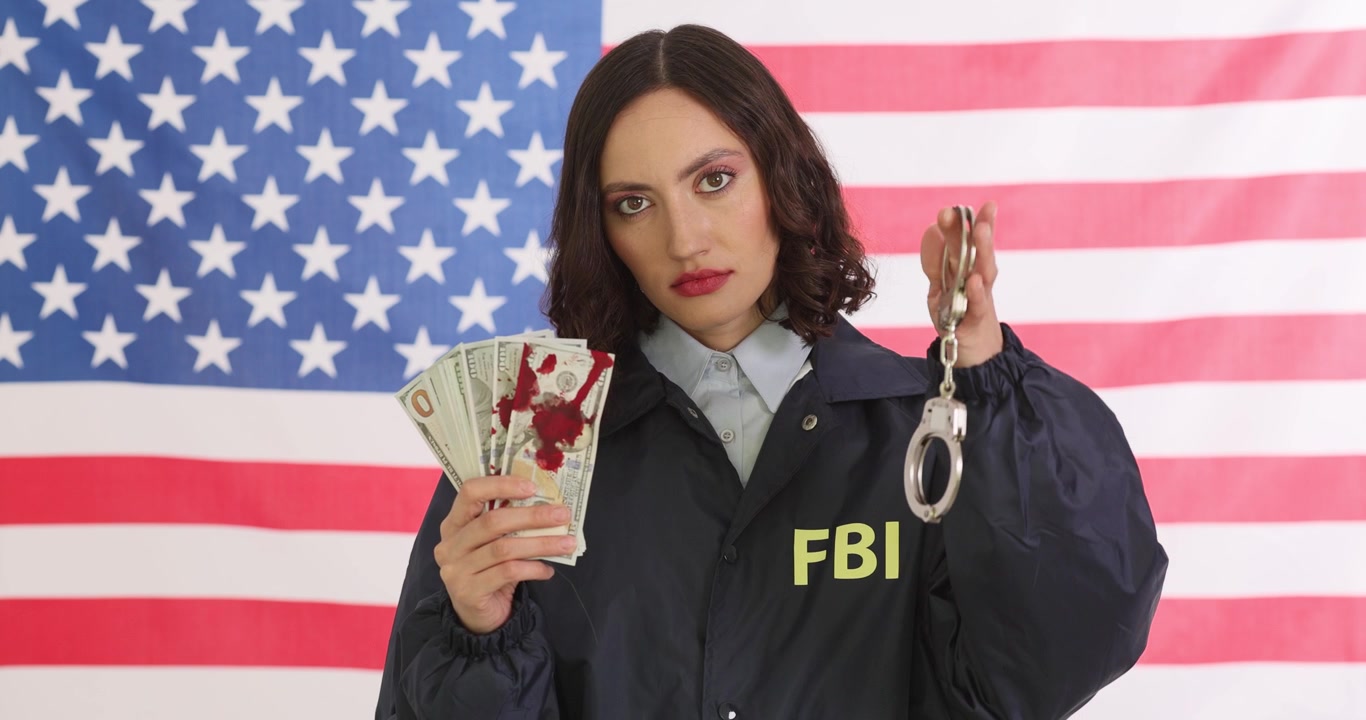 Agente dell'FBI mostra denaro con macchie di sangue rosso e manette