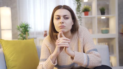 mujer joven pensativa en casa, mujer joven sentada en el sofá en pensamientos profundos.