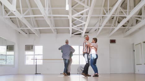 parejas de ancianos caucásicos pasando tiempo juntos en un salón de baile y bailando