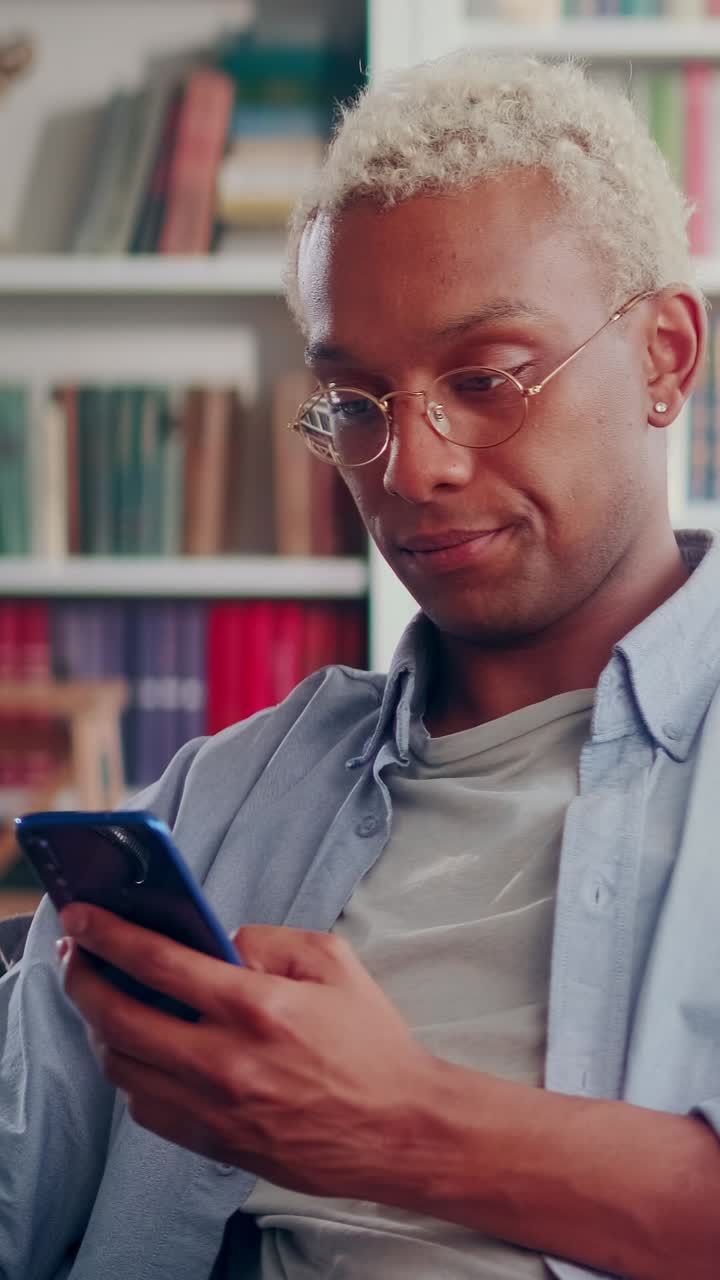 Young excited african american man reads news on phone and restlessly waves head