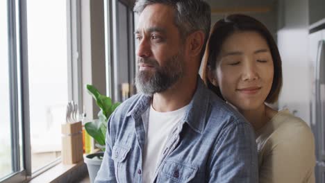 happy diverse couple wearing casual clothes embracing together in kitchen