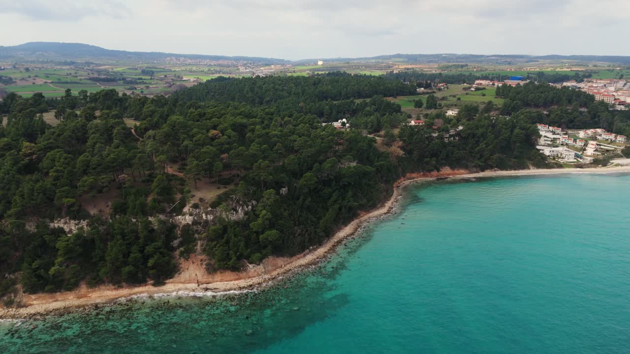Ripresa aerea del litorale con pini e acqua turchese a Kallithea, Calcidica, Grecia