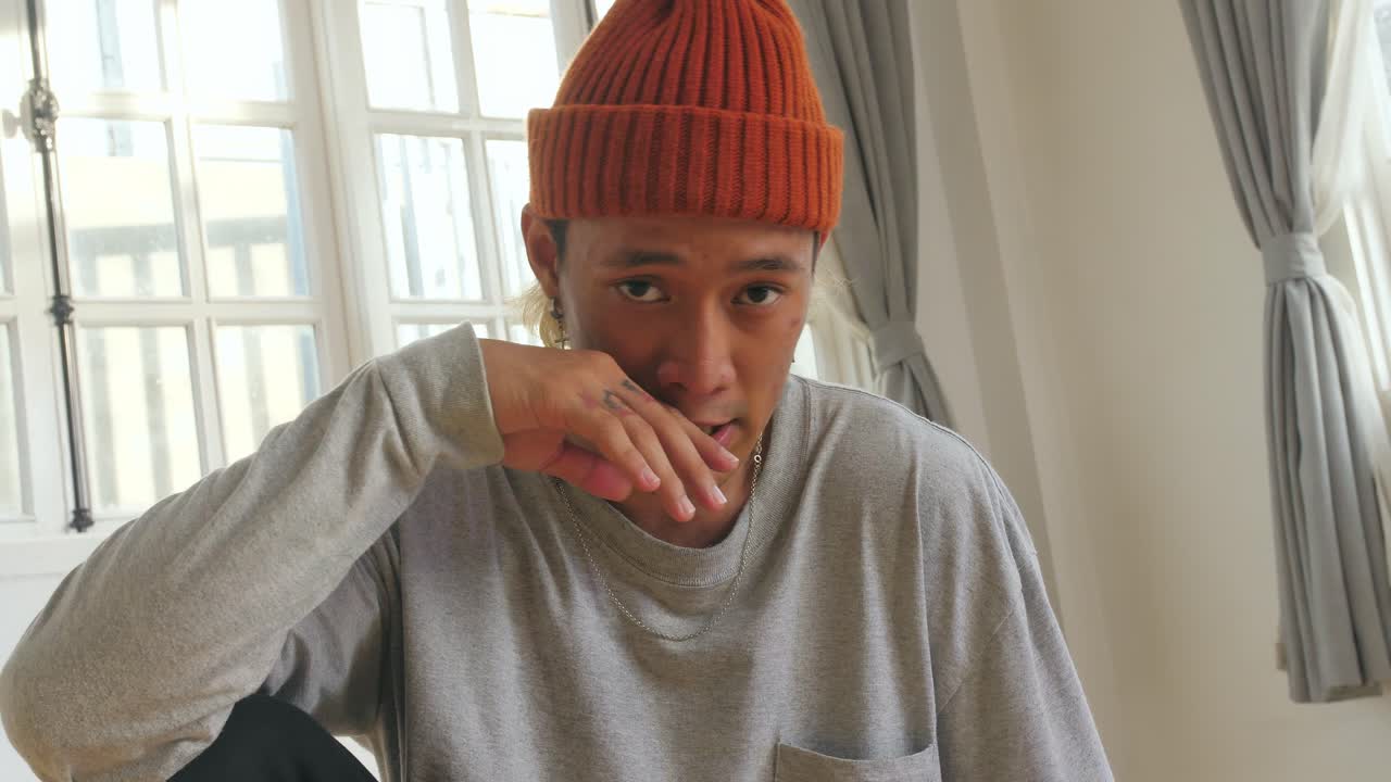Young Man in a Gray Shirt and Orange Beanie