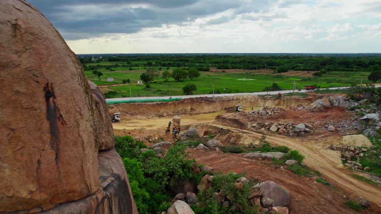 soil mining using excavator to fill a sand in truck in background crop fields lands with sky and clouds in telangana, india. day time, push in, drone shot, 4k