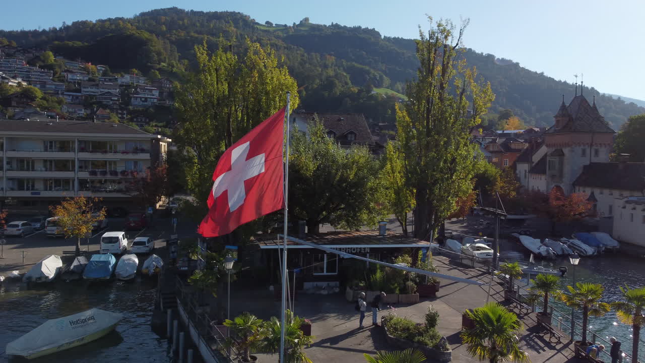 fantástica toma aérea en órbita de la bandera suiza, toma realizada en el municipio de oberhofen en suiza, en un día soleado
