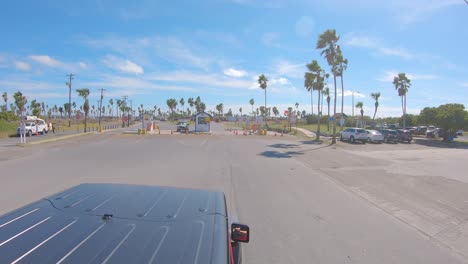 POV-from-roof-top-while-driving-on-Padre-Boulevard-thru-the-guard-post-into-the-Isla-Blanca-Park-on-South-Padre-Island,-Texas