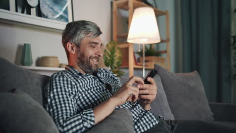 man using smartphone on couch at night