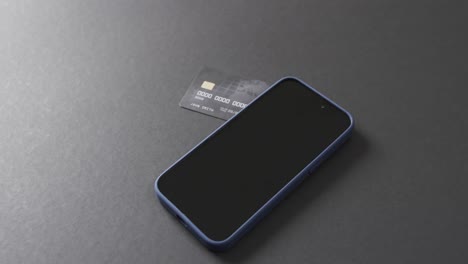 video of smartphone with blank screen, boxes and credit card with copy space on grey background