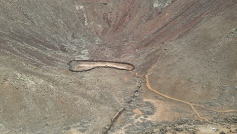 aerial view rising above volcanes de bayuyo crater, fuerteventura rocky volcanic basin interior