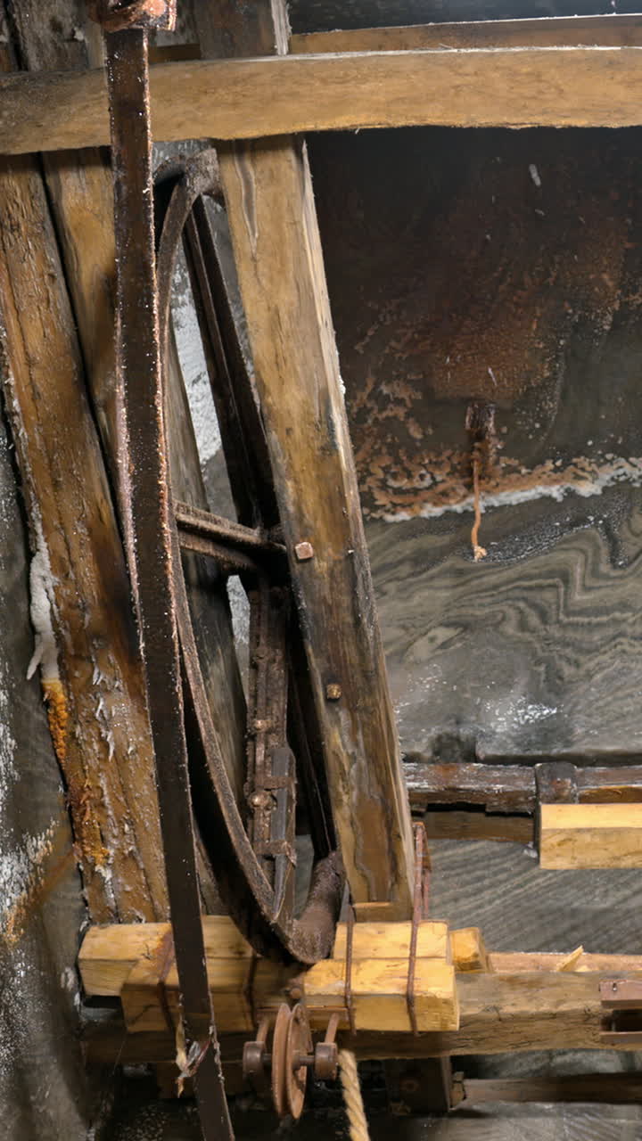 A historic wooden lift system and rusty machinery inside of the Turda Salt Mine in Romania. Vertical