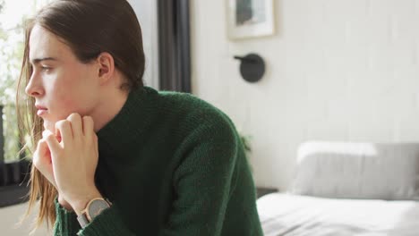 Caucasian-non-binary-transgender-woman-sitting-on-bed-and-thinking