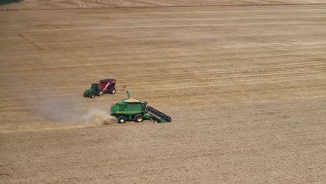 Luftaufnahme-Der-Arbeitenden-Erntemaschine-Und-Traktor-Und-Behälter,-Die-Zum-Entladen-Der-Erntemaschine-Herankommen