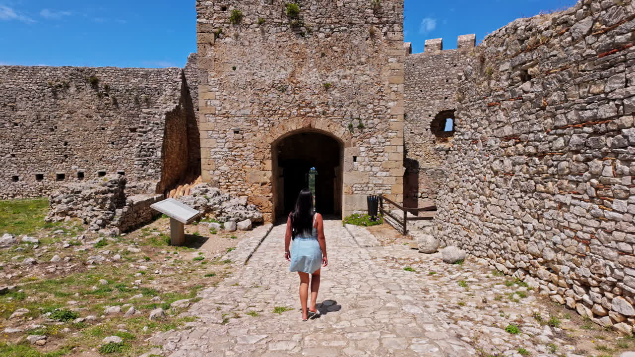 Genç kadın turist antik, taş bir kaleyi ziyaret ediyor
