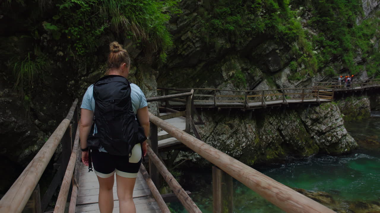 Female hiker crossing boardwalk above river in Vintgar Gorge