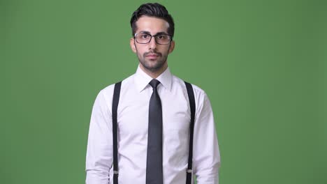 joven empresario persa barbudo y guapo contra un fondo verde