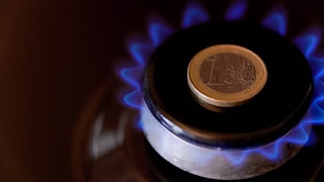 gas stove burner with one euro coin laid on top, burning natural gas with blue flame